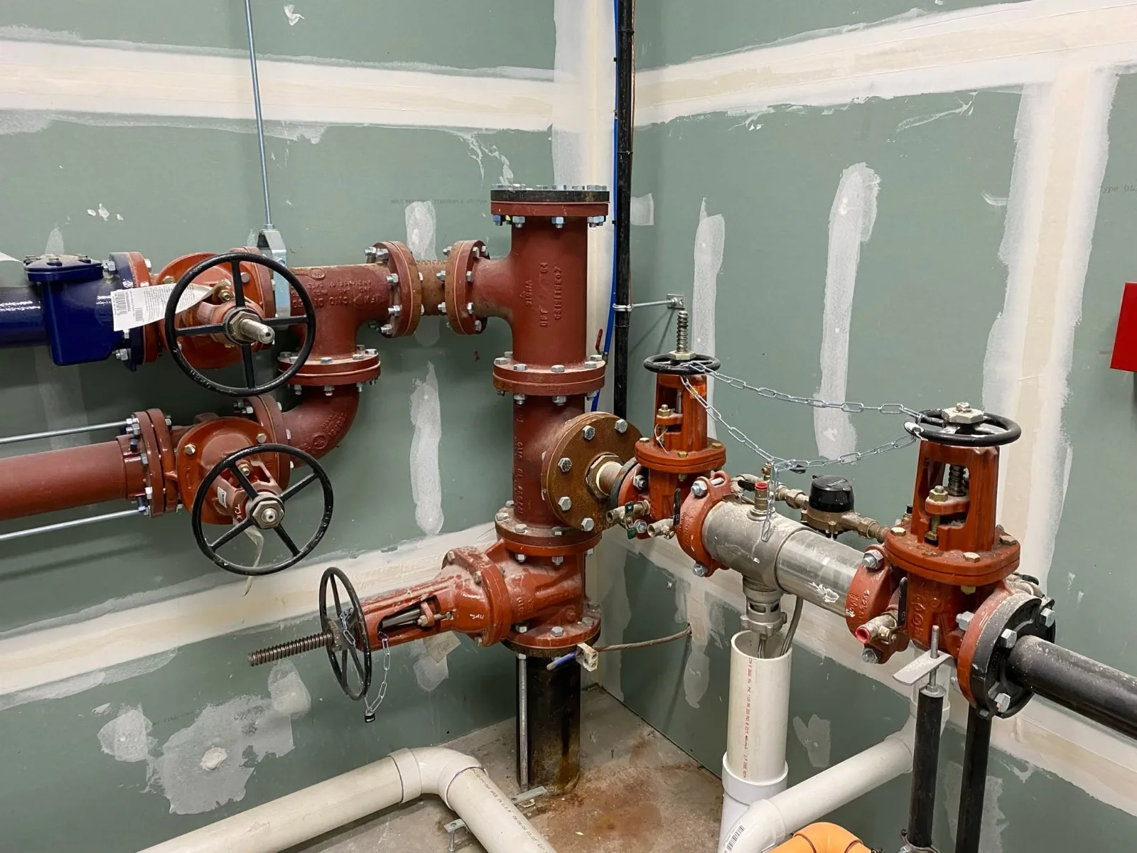 Red iron valves and a backflow preventer on a commercial building’s water service